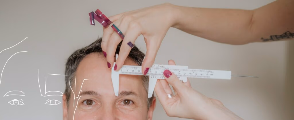 Joice Rossi fazendo análise facial masculina na consultoria de visagismo com paquímetro